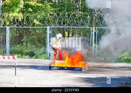 Moskau, Russland - 25. August 2018: Feuer löscht das Feuer mit einem Feuerlöscher, brennende Trog mit Erdölprodukten. Stockfoto