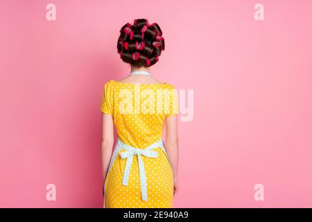 Zurück Rückseite Wirbelsäule Ansicht Foto von anonymen Mädchen stehen Gesicht Isoliert rosa Farbe Hintergrund tragen Haare Rollen Rock Kleid Stockfoto