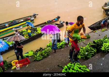 Ein afro-kolumbianischer Arbeiter trägt Früchte beim Entladen von Frachtbooten auf dem Markt des Flusses Atrato in Quibdó, Chocó, der pazifischen Region Kolumbiens. Stockfoto