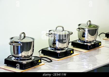 Stahltöpfe auf elektrischen Öfen. Kochen in Pfannen Stockfoto