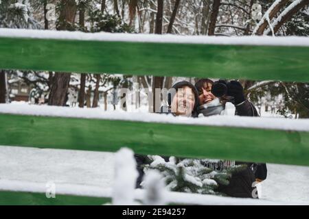 Glückliche Mutter mit Tochter macht Selfie Foto im Spiegel mit Professionelle Fotokamera draußen im verschneiten Winterpark