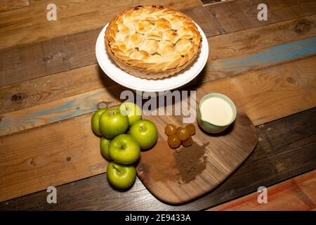 Ein goldbrauner köstlicher gewürzter Apfel- und Stem Ginger Pie auf einem hölzernen Küchentisch, umgeben von den Zutaten, die zum Backen des Apfelkuchen verwendet werden Stockfoto