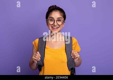 Glückliche indische Studentin trägt Rucksack und Brille Stockfoto