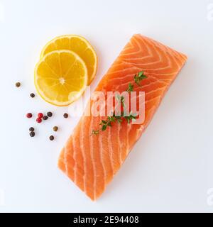Frischer roher, ungekochter Lachs, Filet, Steak, Fisch auf Weiß Hintergrund mit Gewürzen und Zitrone Stockfoto
