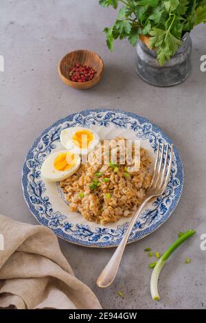 Grober Haferbrei mit Eiern und Zwiebeln. Herzhaftes gesundes Frühstück oder Mittagessen Konzept. Selektiver Fokus. Stockfoto