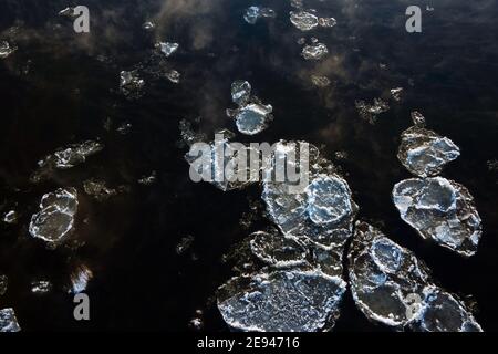 Schmelzen rissiges Eis fließt den Fluss hinunter an einem nebligen Morgen. Neblige Wasseroberfläche am Ende des Winters. Eisdrift. Stockfoto