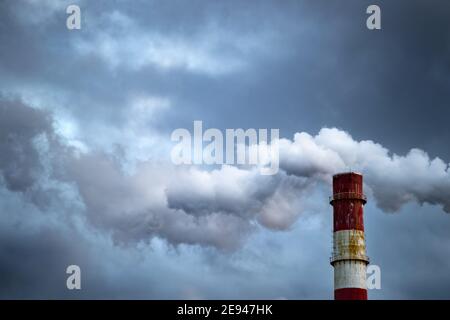 Dunkle giftige Rauchwolken, die aus dem Fabrikschornstein kommen. Luftverschmutzung und Erderwärmung durch altes Industriekraftwerk Stockfoto