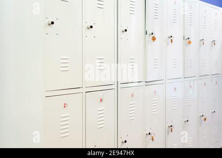 Eine Reihe graumetallener Schulschließfächer mit Schlüsseln in den Türen. Stauraum im Flur der Bildungseinrichtung Stockfoto