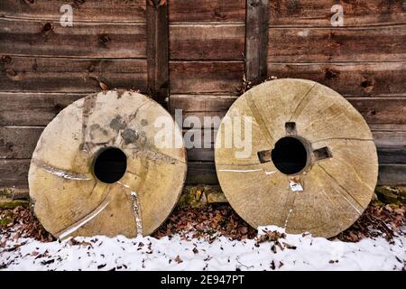 Mühlsteine lehnen sich an alte hölzerne Wassermühle. Stockfoto