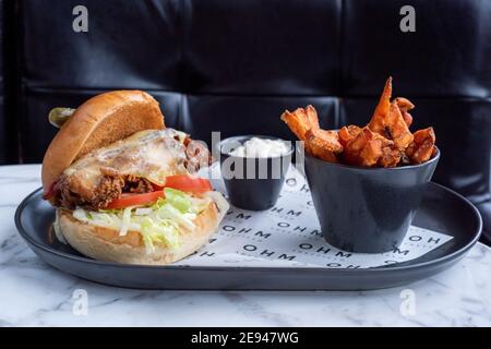 Sheffield, Großbritannien - 03 Aug 2017: Hühnerkäse und Speck-Burger mit Süßkartoffelfries in OHM, Fitzwilliam Street serviert Stockfoto