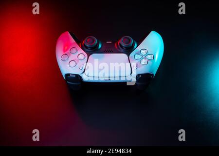 Modernes weißes Gamepad in rot und blau beleuchtet. Game Controller für Videospiele und E-Sports auf dunklem Hintergrund. Stockfoto