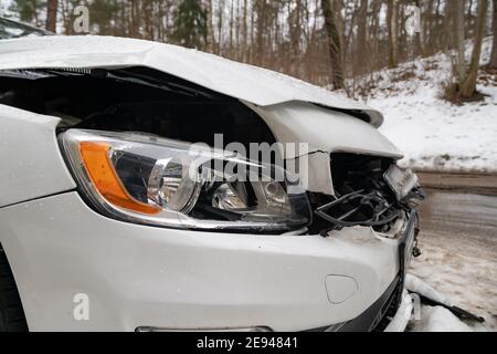 Nahaufnahme eines zertrümmerten Autos nach einem Unfall. Gebrochene Vorderseite des Fahrzeugs nach einem Autounfall in der Stadt. Stockfoto