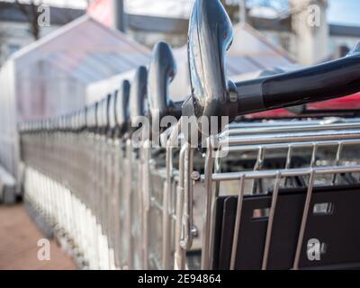 Viele Metall-Einkaufswagen auf einem Parkplatz in der Nähe von Supermarkt im Freien. Stockfoto