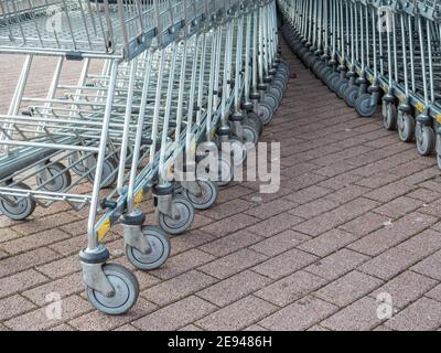Viele Metall-Einkaufswagen auf einem Parkplatz in der Nähe von Supermarkt im Freien. Stockfoto