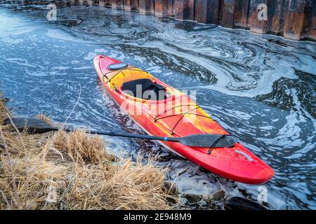 Winter Kajakfahren in Colorado - rotes Wildwasser-Kajak an der Küste Von St. Vrain Creek in der Nähe von Platteville Stockfoto