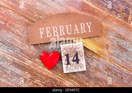 Rotes Herz mit Kalender am 14. Februar auf Holzkäfig. Konzept der Liebe, Hochzeit, Romantik und Alles Liebe zum Valentinstag. Stockfoto