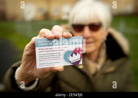 Ältere Dame zeigt ihre Karte als Nachweis der Covid-19-Impfung Stockfoto