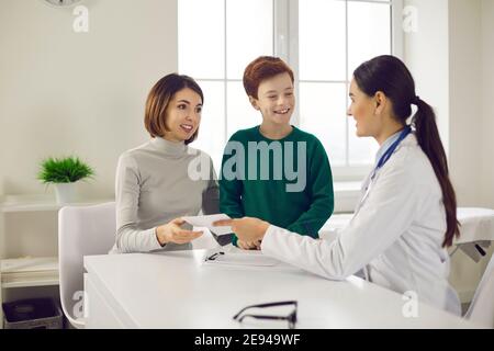 Ärztin gibt der Mutter eines kleinen Jungen ein Rezept für Medikamente. Stockfoto