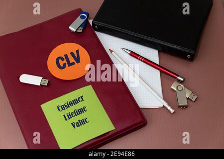CLV - Customer Lifetime Value Akronym auf farbigen Aufklebern. Arbeitstisch mit Notizbüchern zum Schreiben, Speicherkarten und einem Stift Stockfoto