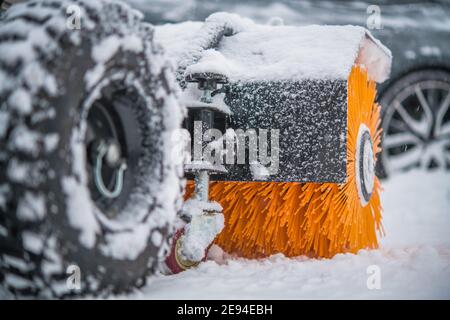 Benzin Bürste Besen Schnee Entfernung Maschine in Aktion bei starkem Schneefall. Wartungsmaschinen Für Die Wintersaison. Stockfoto