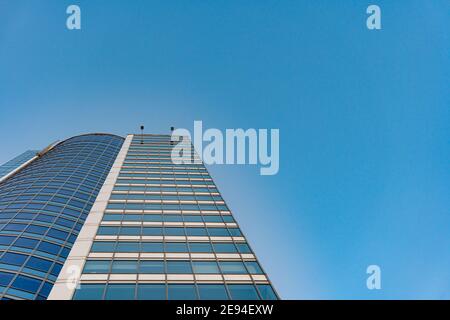 Minsk, Weißrussland - 01. Februar 2021: Blick von unten auf den modernen Wolkenturm im Geschäftsviertel gegen den blauen Himmel Stockfoto