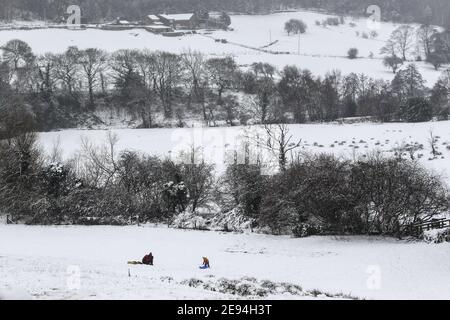 Holmfirth, Großbritannien. Februar 2021. Ein Familienrodeln auf einem verschneiten Hügel in West Yorkshire an einem Dienstagnachmittag. Schwerer Schnee fiel über Nacht in West Yorkshire und verursachte gefährliche Fahrbedingungen. Kredit: SOPA Images Limited/Alamy Live Nachrichten Stockfoto