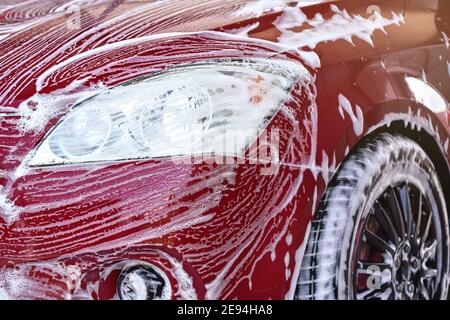 Detail auf roten Auto-Frontlicht in Autowäsche gewaschen, weiße Seife Striche auf der Oberfläche Stockfoto