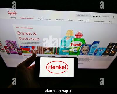 Person, die Smartphone mit Logo des deutschen Chemie- und Konsumgüterunternehmens Henkel auf dem Display vor der Website hält. Fokus auf Telefonbildschirm. Stockfoto