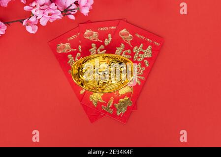 Sakura Blossom, rote Umschläge und goldene Ingot auf rotem Hintergrund Stockfoto