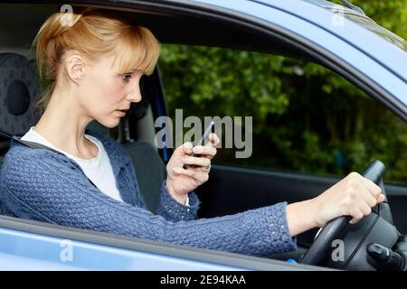 Frau, die zwar mit Handy Stockfoto