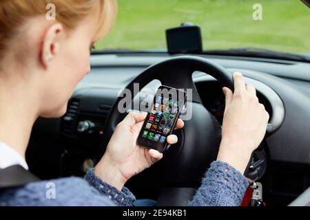 Frau, die während der Fahrt ihr Telefon benutzt Stockfoto