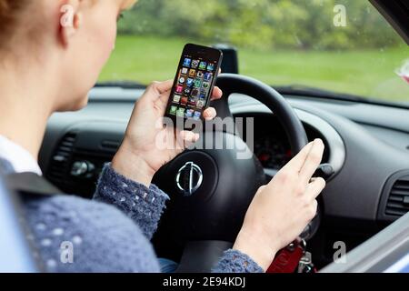 Frau, die während der Fahrt ihr Telefon benutzt Stockfoto