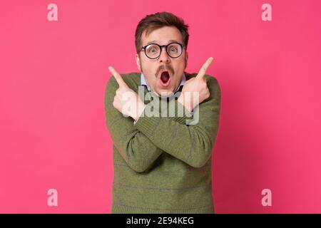 Verwirrt junger Mann zeigt in zwei verschiedene Richtungen, nicht sicher, welchen Weg im Leben zu gehen, zögerlich, Entscheidung zu treffen. Emotion, Gesichtsausdruck Feeli Stockfoto