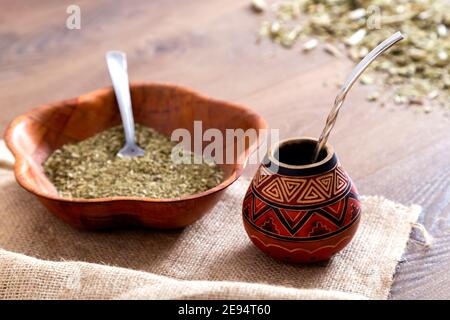 Traditionelle Mate aus Kalabash über einem Holztisch mit Yerba Mate darüber verstreut. Stockfoto