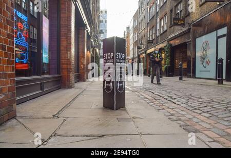 Ein Mann, der eine schützende Gesichtsmaske trägt, geht an einem Schild „Stoppe die Ausbreitung des Coronavirus“ in Covent Garden vorbei, während er abschloss. London, Großbritannien Februar 2021. Stockfoto