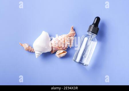 Hautpflege Essenz Öl Tropf in Glasflasche auf blau Hintergrund Stockfoto