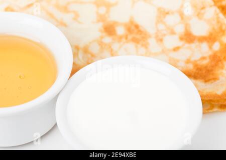 Teil des Frühstücks mit Pfannkuchen und saurer Sahne. Nahaufnahme. Stockfoto