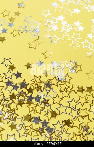 Gold und Silber Sterne Staub funkeln auf gelb. Chaotischer kosmischer Hintergrund mit goldenen Sternelementen fliegen. Gold Glitter Staub Konfetti, Magie glänzend funkelt streuen. Festliche Einrichtung mit Sternenhimmel. Stockfoto