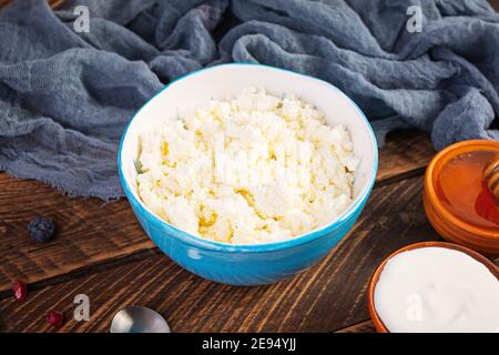Hüttenkäse mit Honig und Beeren auf Holzhintergrund. Leichtes vegetarisches Frühstück. Stockfoto