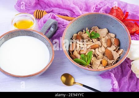 Dinkelflocken mit Milch zum Frühstück. Leichtes Frühstück am Valentinstag mit Tulpen und Herz Stockfoto