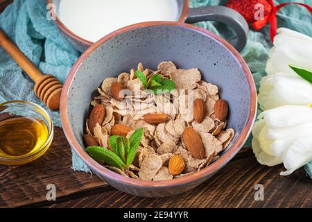 Dinkelflocken mit Milch zum Frühstück. Leichtes Frühstück am Valentinstag mit Tulpen und Herz Stockfoto