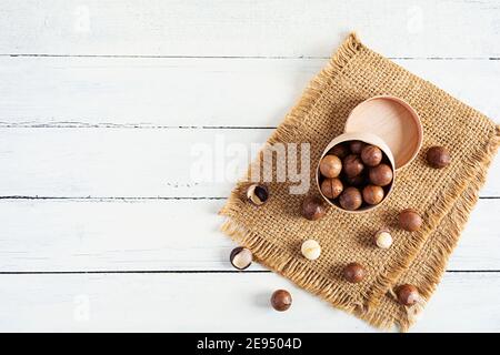 Macadamianüsse in Schale auf Holzhintergrund. Draufsicht Stockfoto