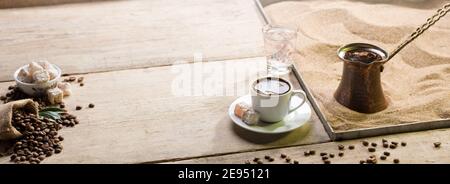 Traditionelles türkisches Kaffeekochkonzept in Sand. Es wird mit türkischem Genuss und Wasser serviert. Stockfoto