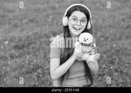 Sommerspiel. Happy Girl spielen mit Teddybär auf grünem Gras. Kindheitsspiele zu spielen. Aktivitäten im Freien. Entwicklung und Wachstum von Kindern. Spielen mit Spielzeug. Spielwarenladen. Spielen Sie, um Phantasie zu entwickeln. Stockfoto