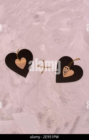 Zwei Herzen aus Graphit und Holz auf grauem texturiertem Hintergrund. Herz plus Herz zusammen. Konzept für Valentinstag, Liebhaber, Hochzeit. Stockfoto