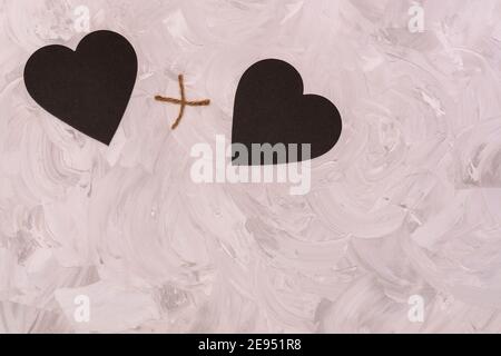 Herz plus Herz zusammen. Zwei schwarze Graphitherzen auf grauem texturiertem Hintergrund. Platz für Text kopieren. Konzept für Valentinstag, Liebhaber, Hochzeit. Stockfoto