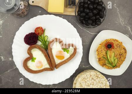 Herzförmige Würstchen und Rühreier für ein romantisches Frühstück. Ein originelles und lustiges Frühstück für einen geliebten Menschen. Frühstück am Valentinstag Stockfoto