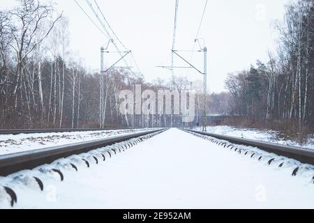 Die Schienen sind im Winterwald mit Schnee bedeckt. Schienen aus der Fahrerkabine Stockfoto