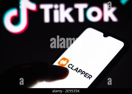 In dieser Abbildung wird das Clapper-Logo auf einem Smartphone-Bildschirm mit dem TikTok-Logo auf einem Computerbildschirm im Hintergrund angezeigt. Stockfoto