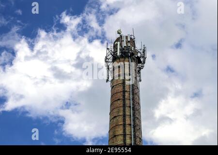 5G Antennen auf einem Ziegelrohr gegen einen wolkigen Himmel. Mobilfunkantennen und Internet auf dem Ziegelrohr des Kesselraums. Stockfoto